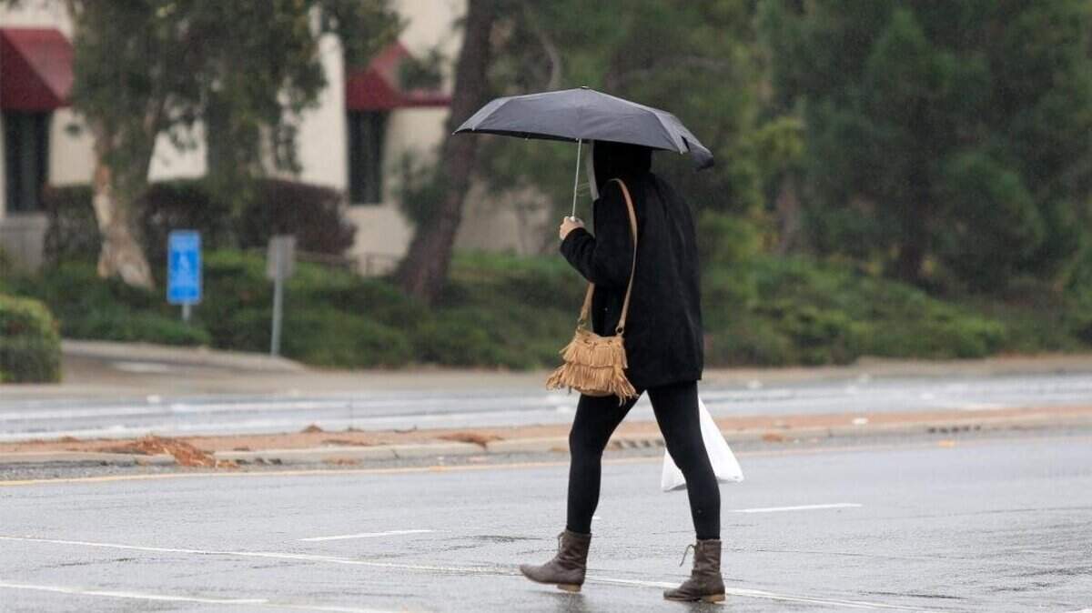 Scattered showers and some steady rain in some areas finally reach the Central Coast late morning. Forecast show that the rain will become heavier later this afternoon and evening. A woman crosses the intersection of Foothill Rd and Santa Rosa in the rain.