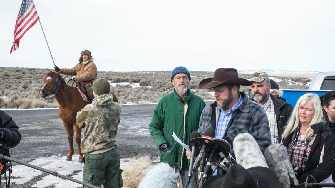 Neil Sigurd Wampler (center, green coat), 68, of Los Osos is among the militia members taking part in the armed occupation at the Malheur National Wildlife Refuge outside Burns, Oregon. According to court records and authorities, Wampler was convicted of murder in Lake County in 1977. Here, he listens as leader Ammon Bundy speaks at a morning press conference near the gate to the refuge on Jan. 14.