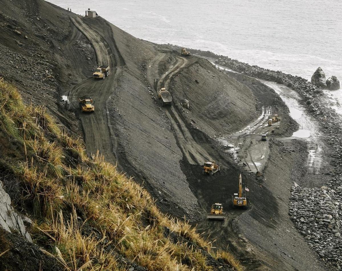 At the Mud Creek Slide site, crews in heavy machinery use access roads to truck down boulders that will armor the beach and bolster the shelves of earth that will support the new stretch of Highway 1 on the Big Sur coast.