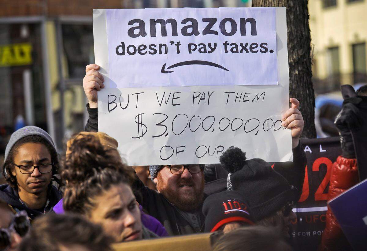 In this Nov. 14, 2018 file photo, protesters hold up anti-Amazon signs during a coalition rally and press conference of elected officials, community organizations and unions opposing Amazon headquarters getting subsidies to locate in Long Island City, in New York. (AP Photo/Bebeto Matthews, File)