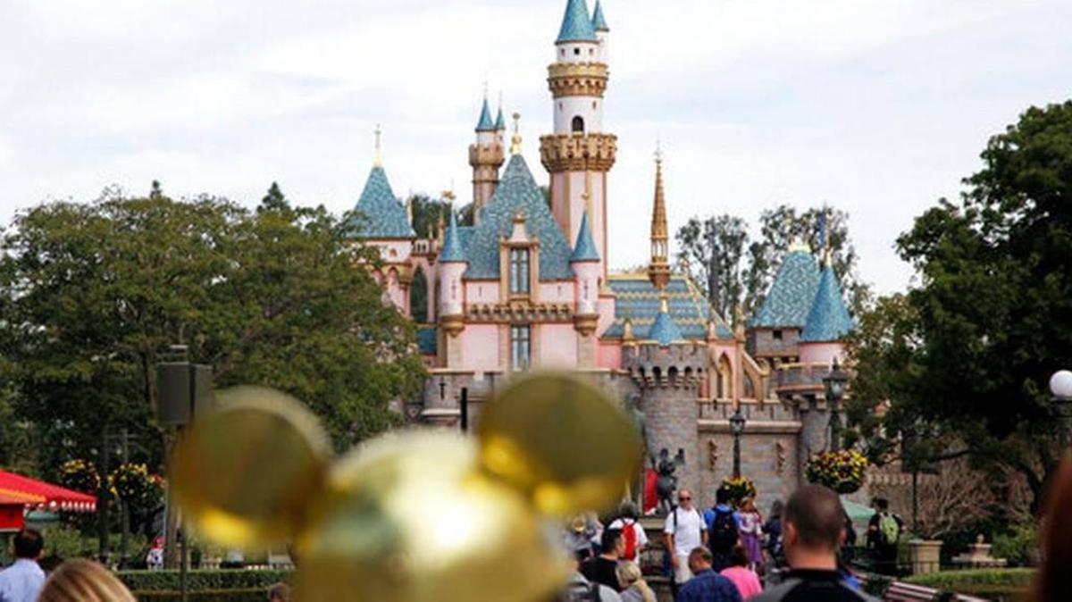 In this Jan. 22, 2015, file photo, visitors walk toward the Sleeping Beauty's Castle in the background at Disneyland Resort in Anaheim, Calif.