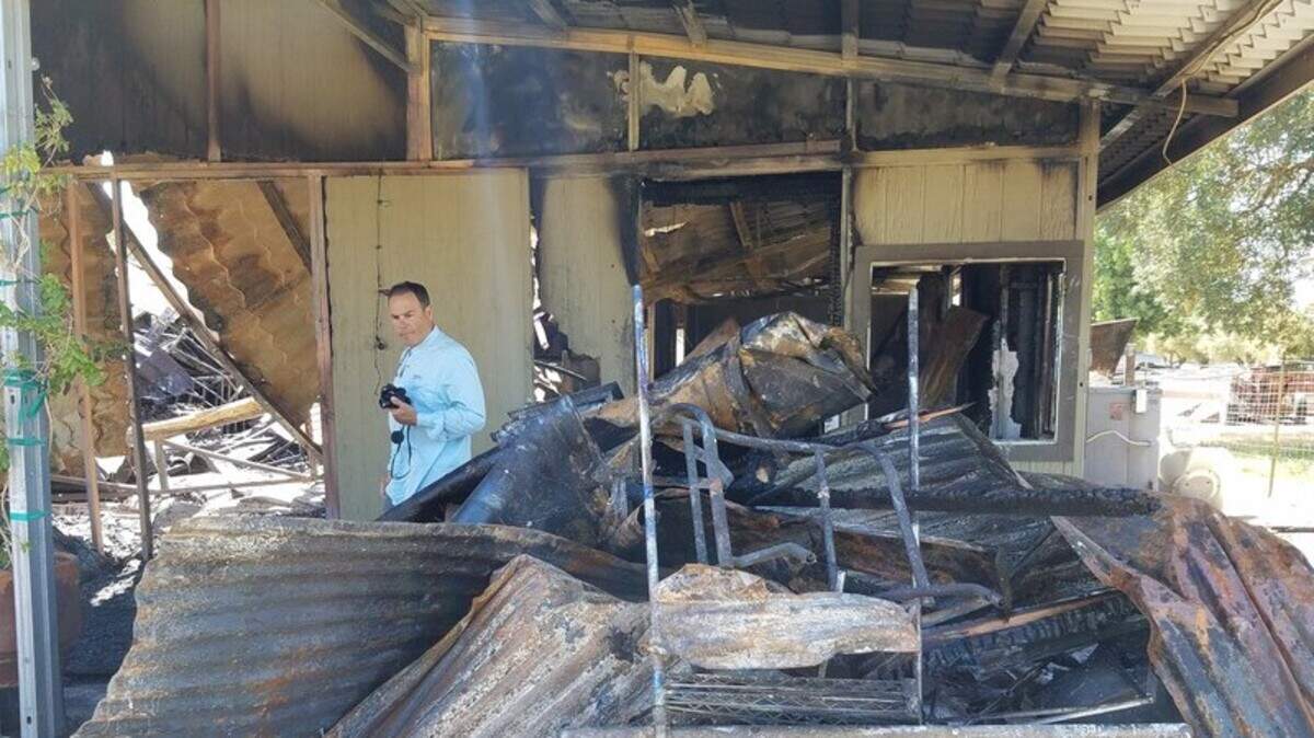 A man surveys the remains of the Olivias de Oro Olive Co. tasting room, which burned down June 15.