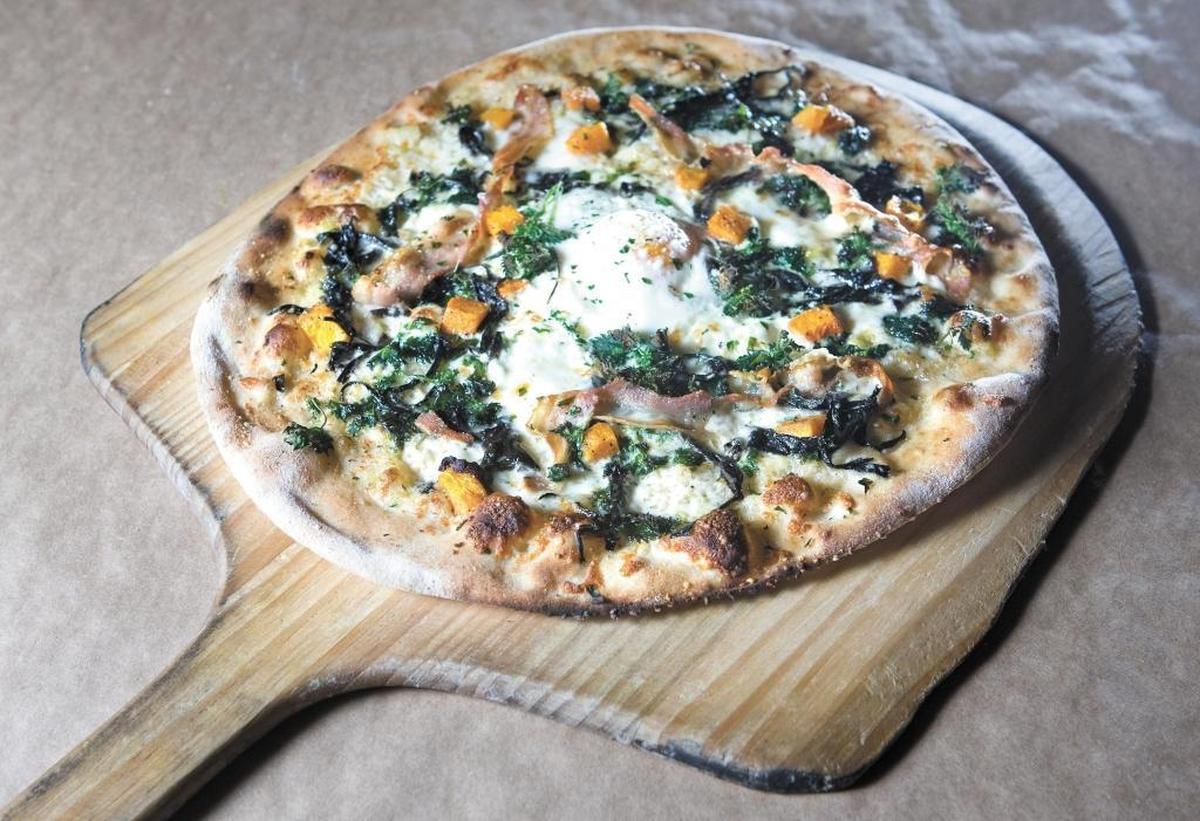An Ember pizza is topped with black trumpet mushroom, nettles, farm egg, smoky white sauce, pancetta, butternut squash and garden thyme. The restaurant was named one of 38 essential California restaurants by the dining website Eater.