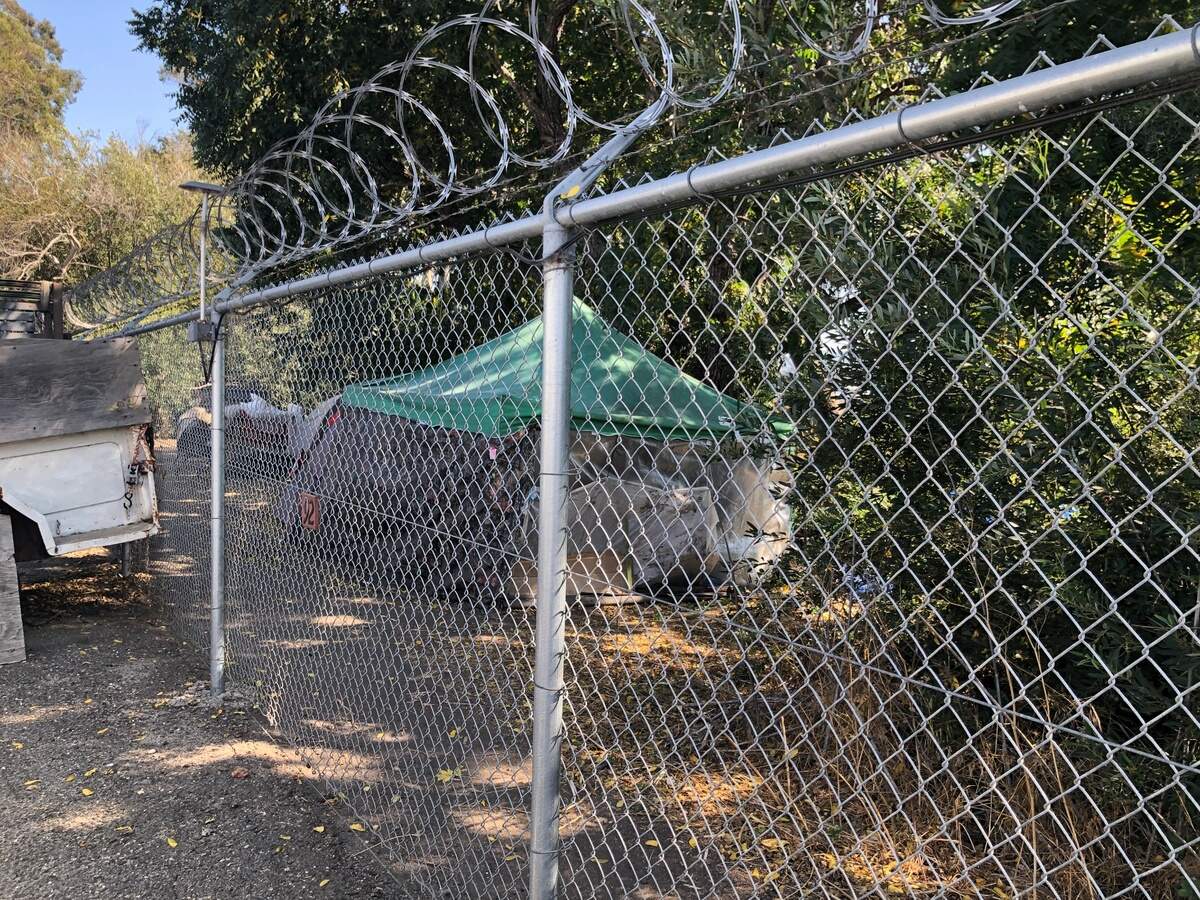 A tent is set up beyond the fence near the Elks Lodge RV storage area.