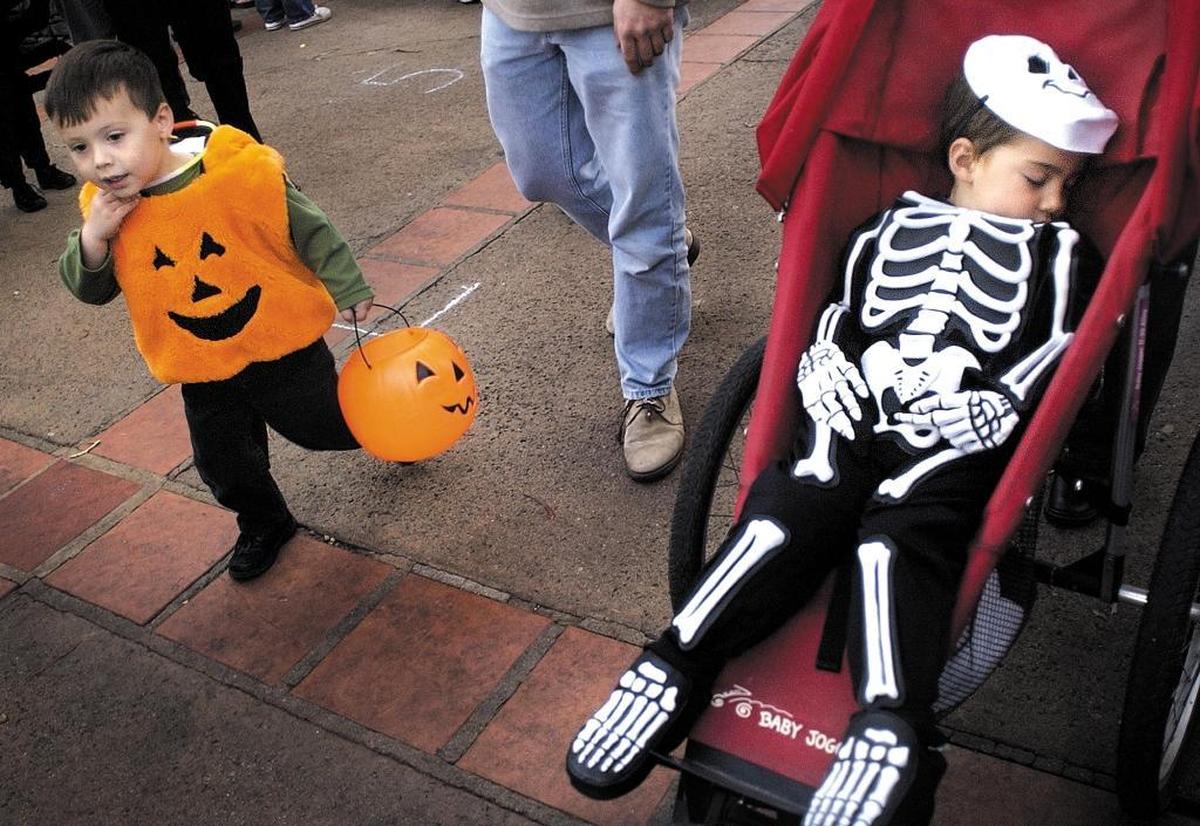 Griffin Scotti, 3, walks past a sleeping Isaac Lerner in Mission Plaza during the Halloween festivities at Farmers Market in 2004. Rain has pushed downtown trick-or-treating from Thursday to Monday.