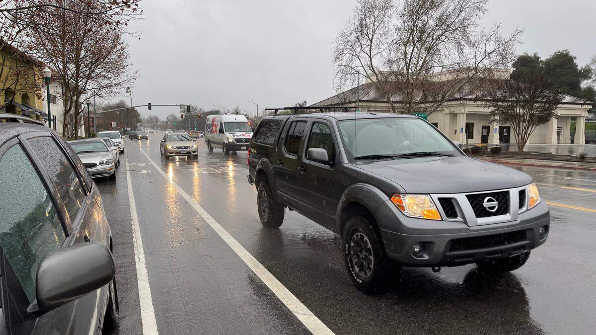 Traffic drives slowly on El Camino Real as rain falls in downtown Atascadero on Jan. 14, 2023.