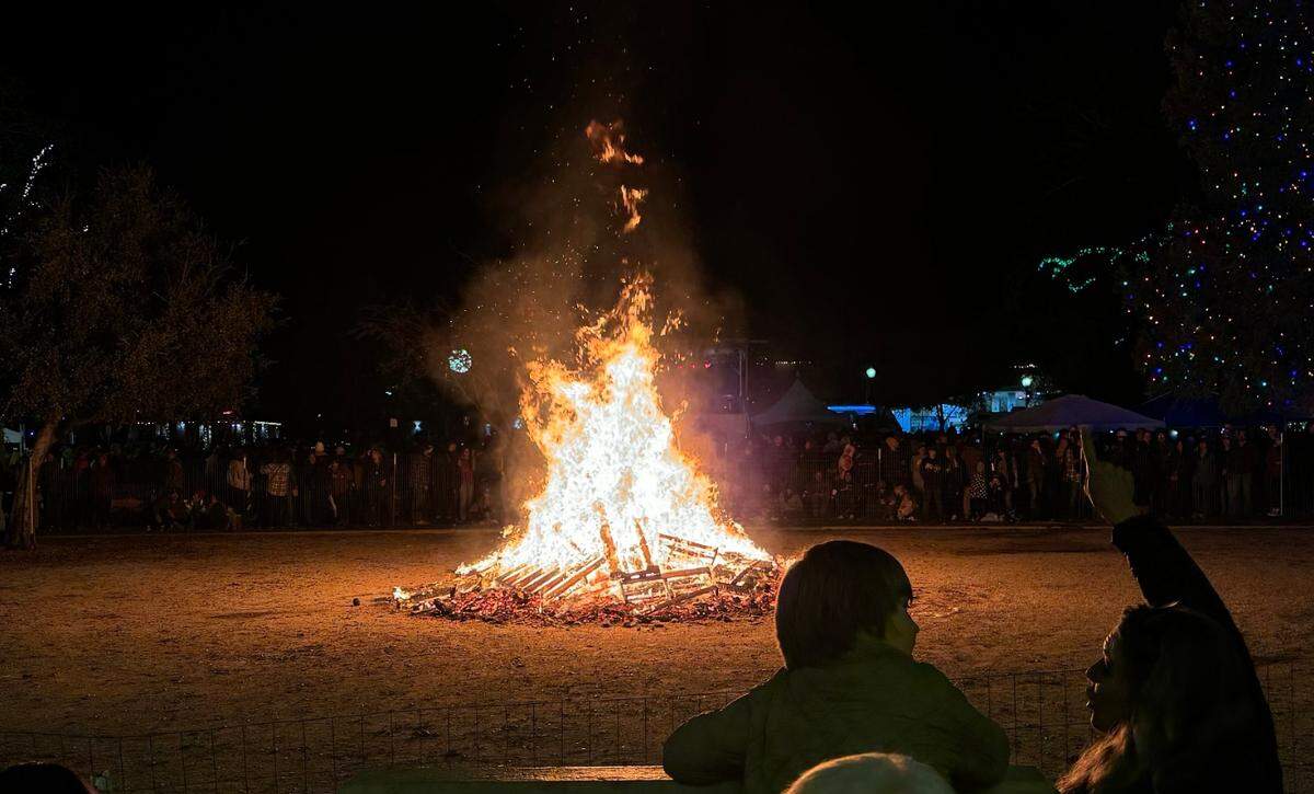 Revelers circle around the giant bonfire during Paso Robles’ New Year’s Eve celebration at the Downtown City Park on Dec. 31, 2023.