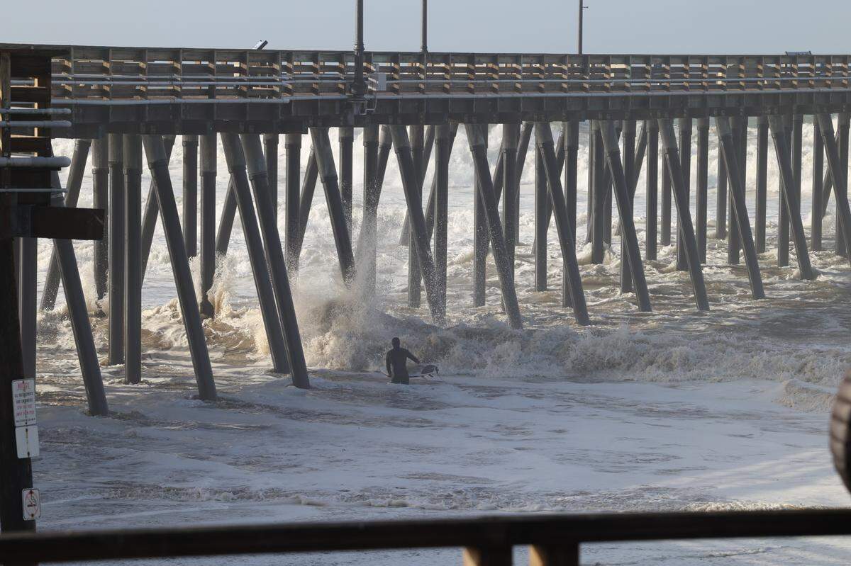 A surfer heads out into big waves shortly after high tide in Pismo Beach after a big storm passed through on Jan. 5, 2023.