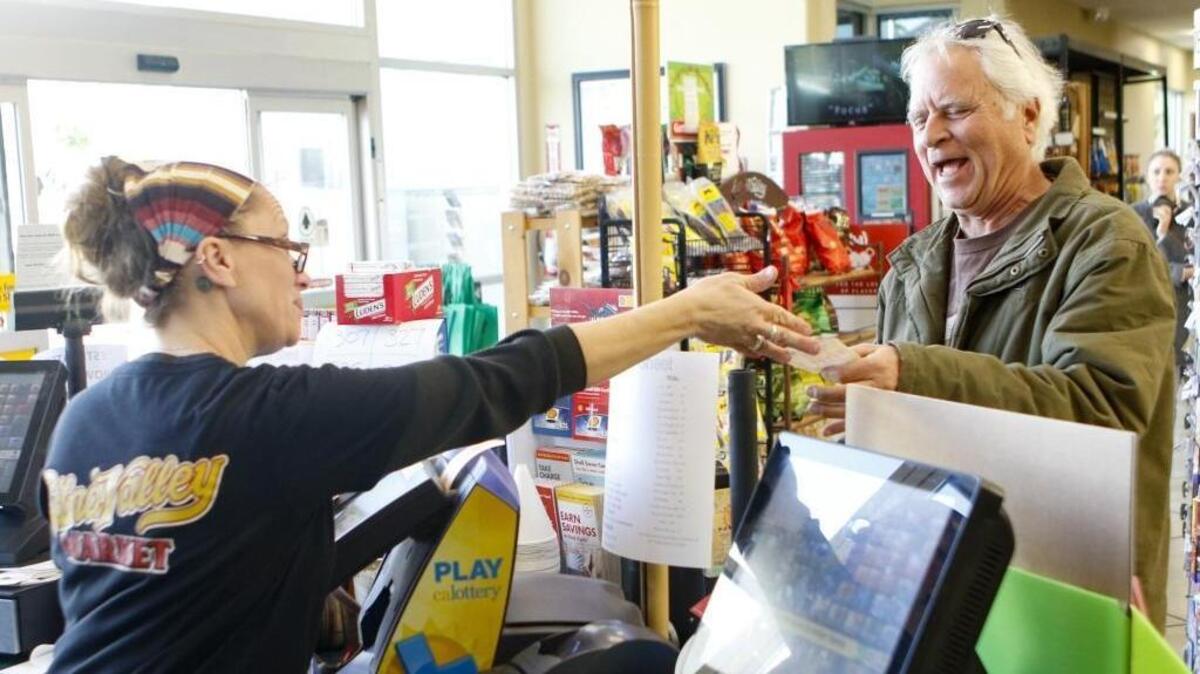 Clerk Sonja Rogers hands Mark Snider his Powerball ticket at Edna Valley Market in San Luis Obispo.