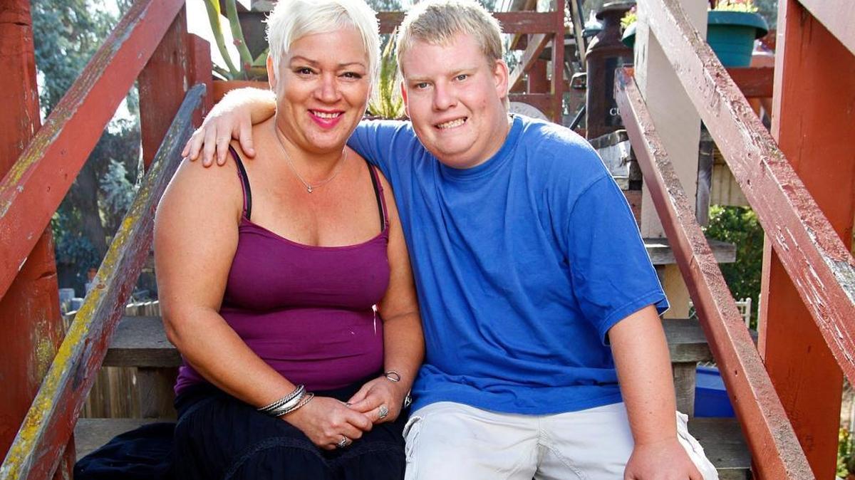 Tyler Jarvis, who has Prader-Willi Syndrome, sits with his mom, Michelle Christian, at their Pismo Beach home.