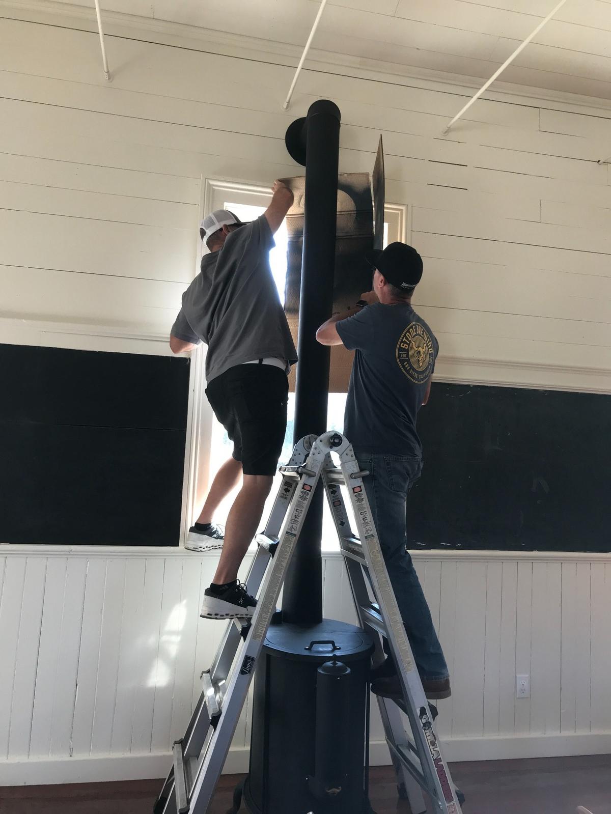 Brian Snow, left, and his twin brother Paul Snow, both raised in Cambria, put the finishing touches on a circa 1880s Northwest Stove Works stove from Oregon. It had been in the Santa Rosa School for about seven decades before the stove was removed in 1952. The brothers restored the historic stove and reinstalled it in late October 2023 in the one-room schoolhouse, now a demonstration museum for the Cambria Historical Society.