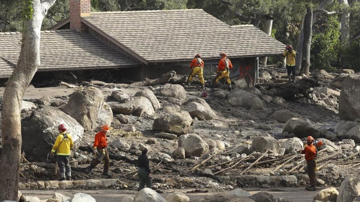 Inmate firefighters and their supervisors work at a home inundated by the mudslide in Montecito, on Jan. 15, 2018.
