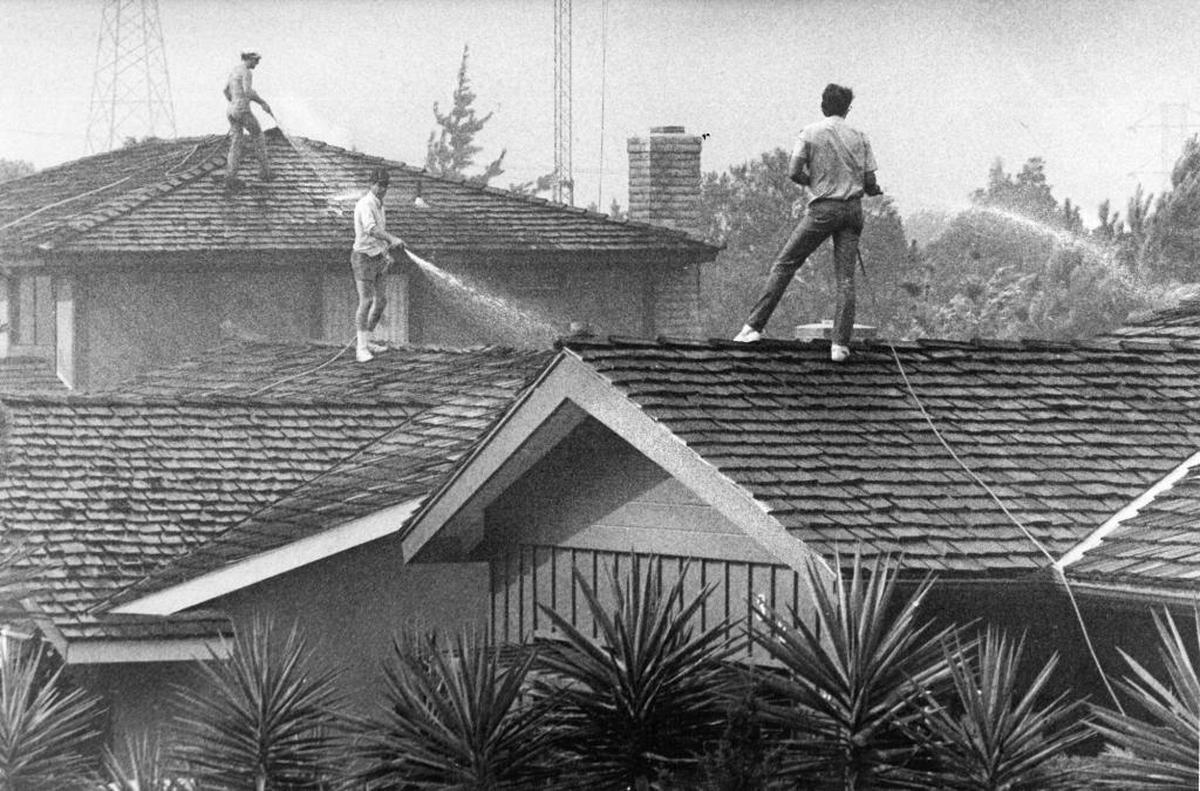 Residents of Flora Street hose hose down shake roofs in San Luis Obispo. The Las Pilitas Fire began July 1, 1985. The nine-day fire consumed 75,000 acres of brush and 10 homes. It cost $6.3 million and jumped fire lines twice.