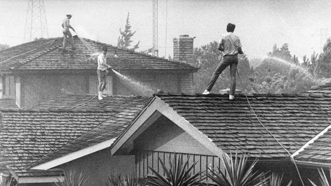 Residents of Flora Street hose hose down shake roofs in San Luis Obispo. The Las Pilitas Fire began July 1, 1985. The nine-day fire consumed 75,000 acres of brush and 10 homes. It cost $6.3 million and jumped fire lines twice.