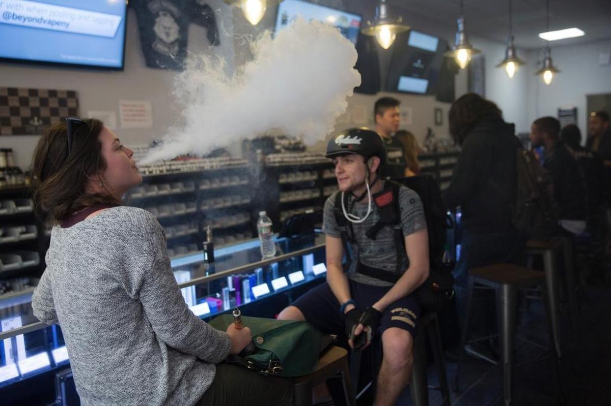 Customers smoke e-cigarettes at Beyond Vape, a store in New York on April 16, 2015. Morro Bay and Arroyo Grande have passed vaping sales bans.