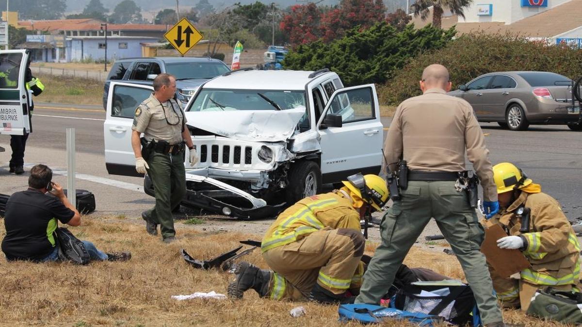 CHP officers inspect the scene of a crash Wednesday at Vista Del Mar and Highway 1 at the south end of San Simeon while paramedics work to aid one of the German tourists injured in the collision.
