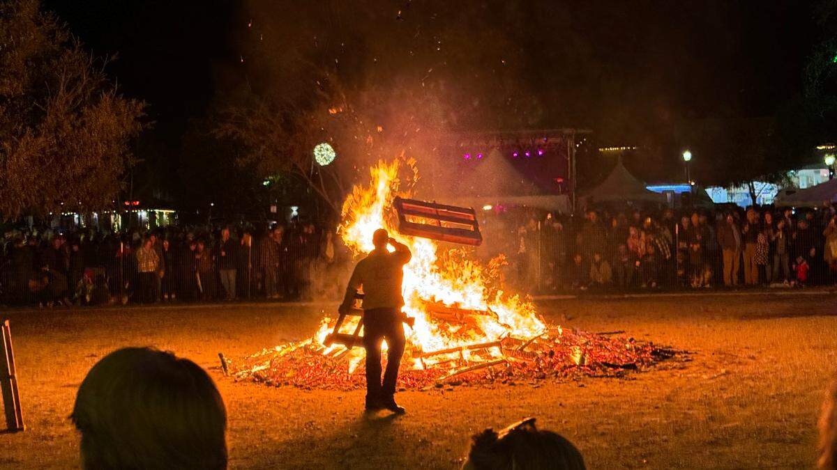 A firefighter throws a pallet onto the giant bonfire at Paso Robles’ New Year’s Eve celebration in the Downtown City Park on Dec. 31, 2023.