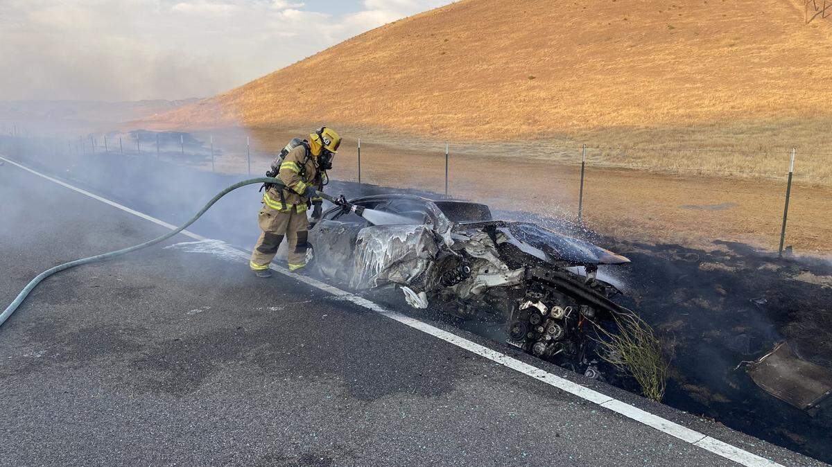 A firefighter sprays a vehicle that caught on fire after a woman traveling on Highway 41 veered off the road and crashed into a concrete drain. The CHP has not yet released the name of the woman, who died from injuries she sustained during the crash.