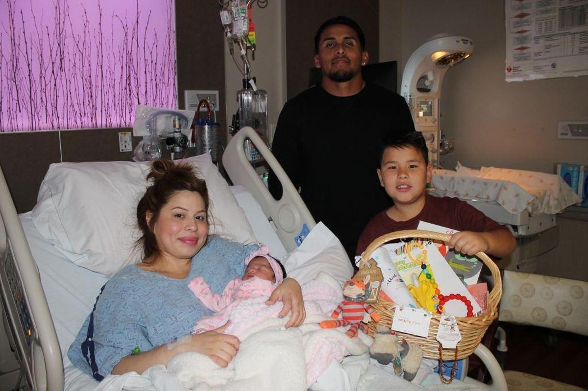 New parents Leanne and Jesus Rivera hold Olivia Faith Rivera, the first baby born in SLO County in 2018. Olivia’s older brother, Zach Lyons, holds a gift basket for the baby.