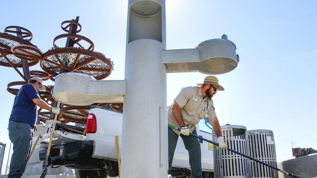 City parks department workers Billy Harvey, left, and David Parson perform landscaping work Tuesday near a water bottle refill station (the center post between drinking fountains) at the SLO Skate Park.