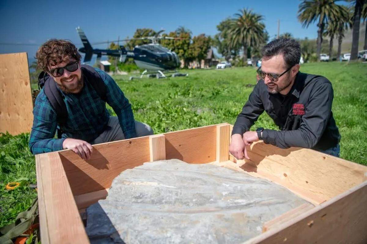 Chris Driesbach, left, and Jonathan M. Hoffman, a curator at the Santa Barbara Museum of Natural History, stand over a piece of the whale fossil found along the Gaviota Coast. The fossil was broken up into pieces and transported by helicopter.