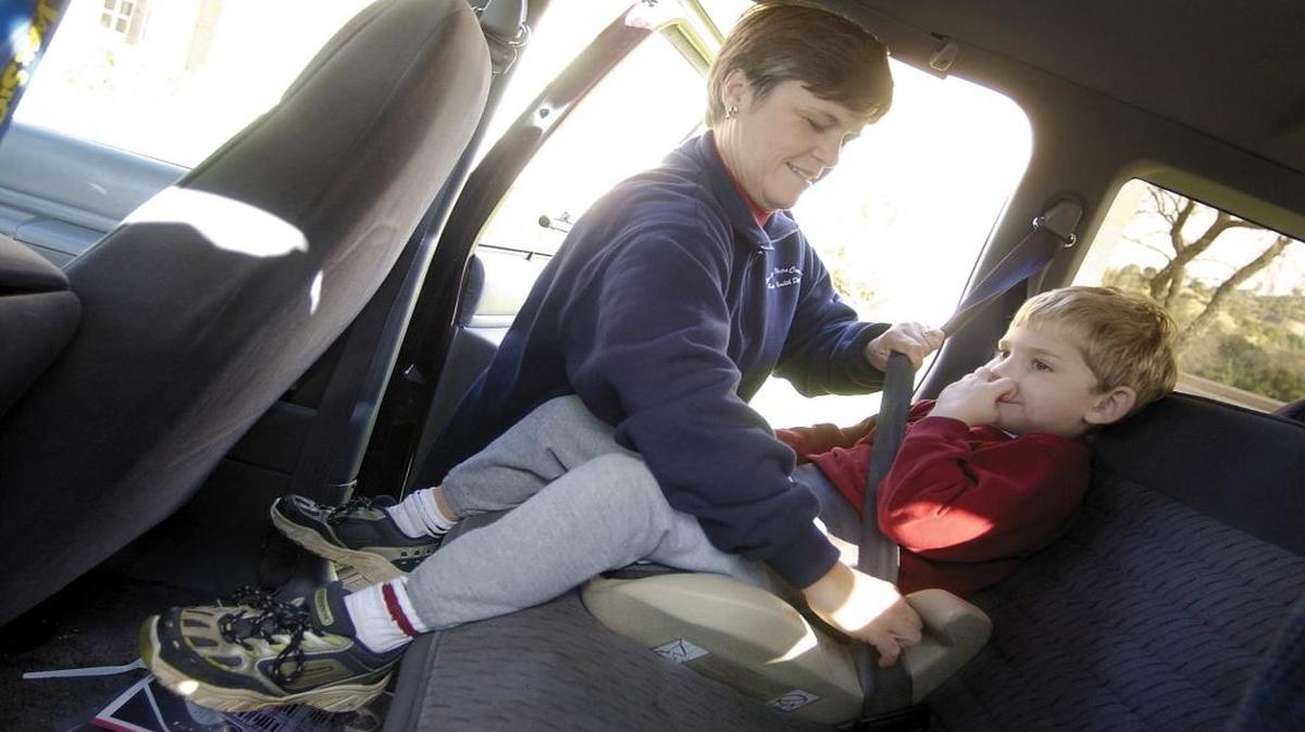 Barbara Baranek demonstrates how to buckle Joseph Casacca, 5, into a car seat for older children.