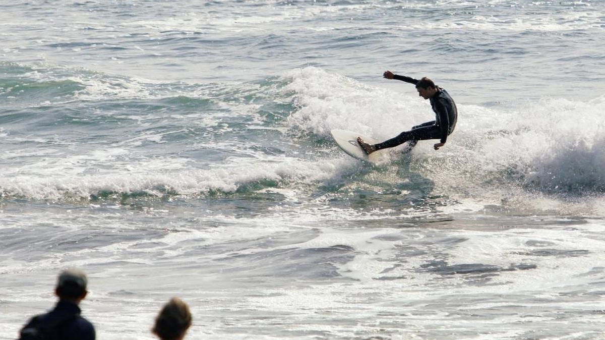 Beachgoers watch a surfer in Cambria recently.