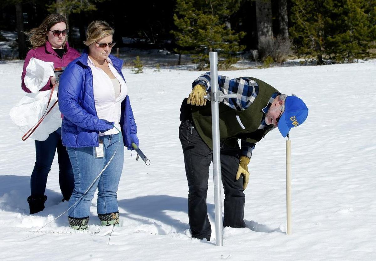 Frank Gehrke, right, with the Department of Water Resources checks the snowpack depth as Courtney Obergfell, left, and Michelle Mead, center, both of the National Weather Service, look on during the second snow survey of the season Thursday near Echo Summit, Calif. The snow survey showed the snow pack at this location at 13.6 inches of deep with a water content of 2.6 inches.