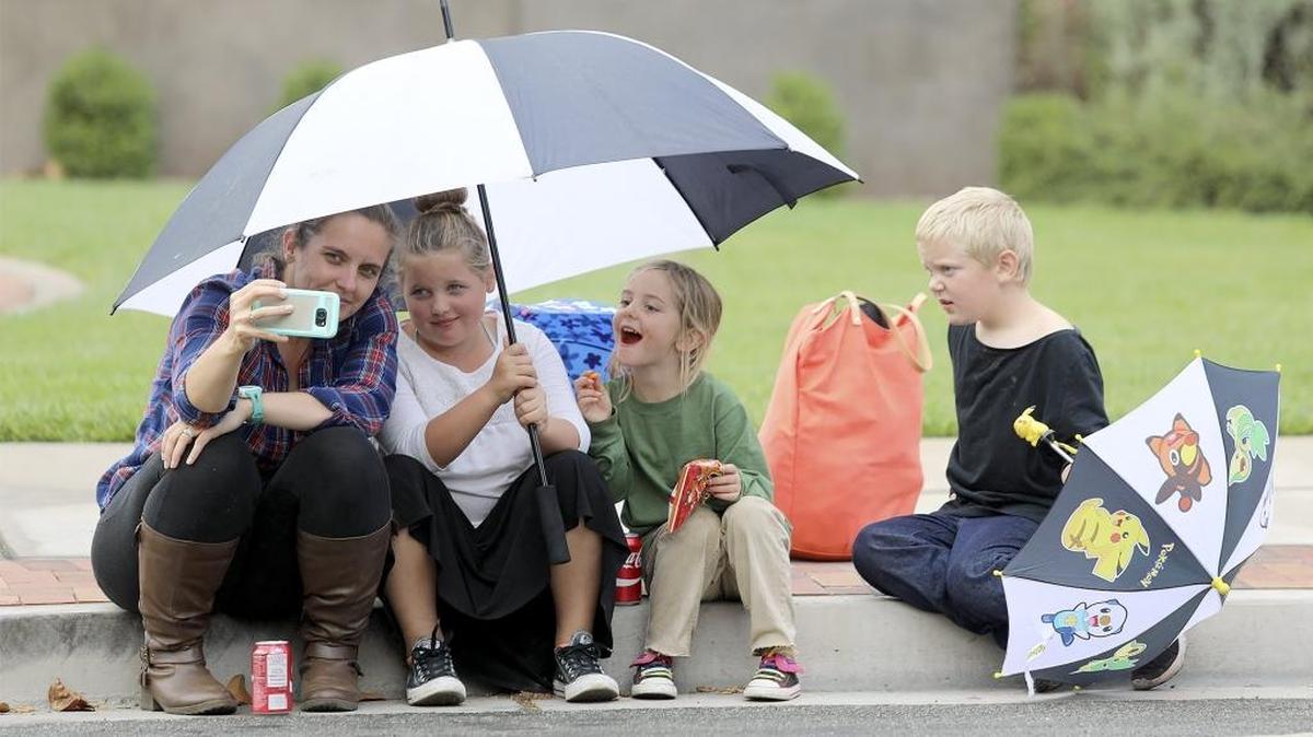 Rachel Hunter, of Atascadero and her children, Julie, 9, Sadie, 4, and Andy, 8, sit under umbrellas to stay dry during a light drizzle at the Colony Days festival in Atascadero on Saturday.