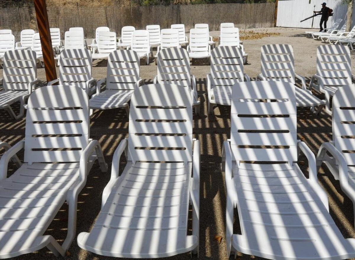 Pedro Bustamonte blows leaves away from lounge chairs at the Ravine Waterpark in anticipation of a holiday weekend crowd in Paso Robles.