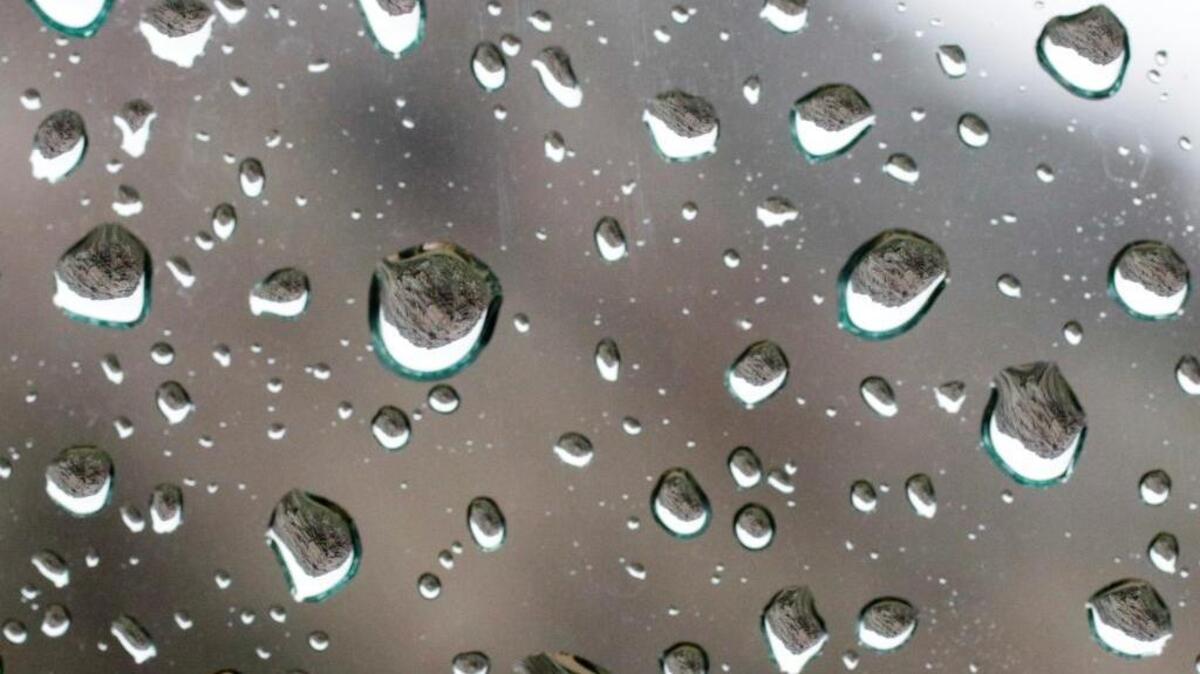 Morro Rock is inverted in the raindrops on this car window.