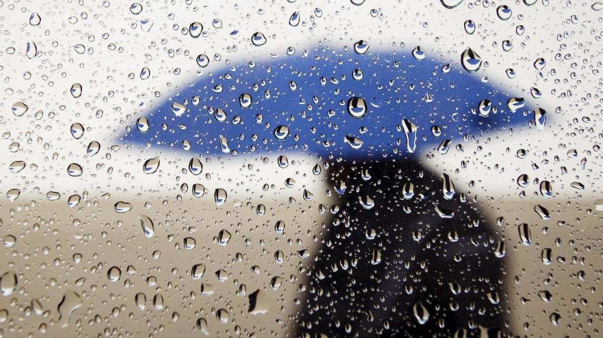 Rain pelts a man walking with an umbrella in downtown San Luis Obispo in December 2015.
