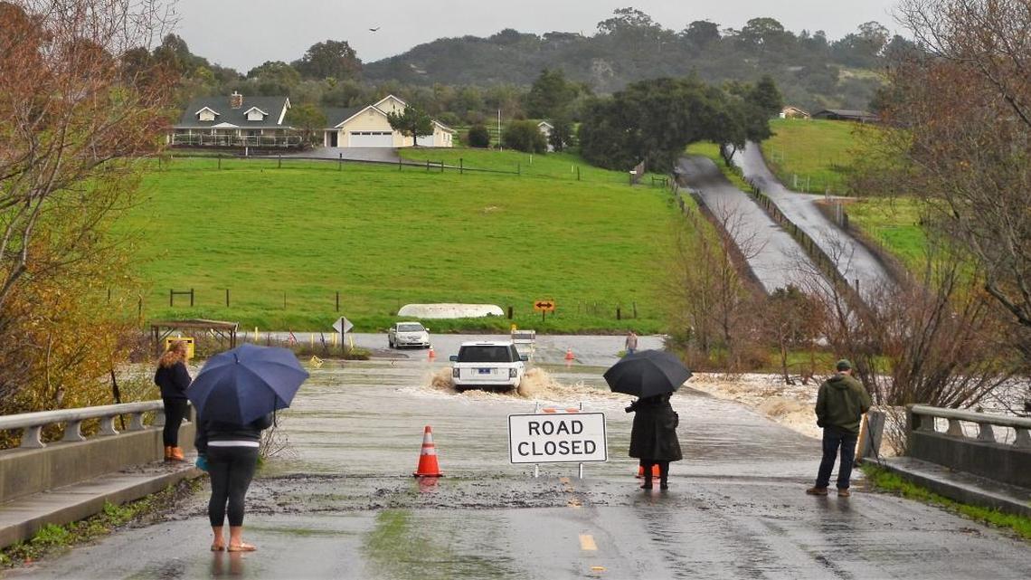 A driver of an SUV takes a risk Friday crossing a flooded San Luis Creek in Avila Valley.