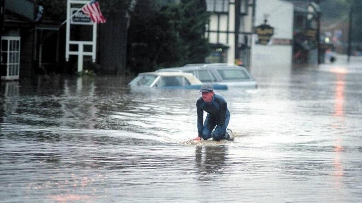 A surfboard was the preferred vehicle for getting around Main Street in the West Village of Cambria on March 10, 1995, when heavy rains and high tides combined to flood the town with the waters of Santa Rosa Creek.