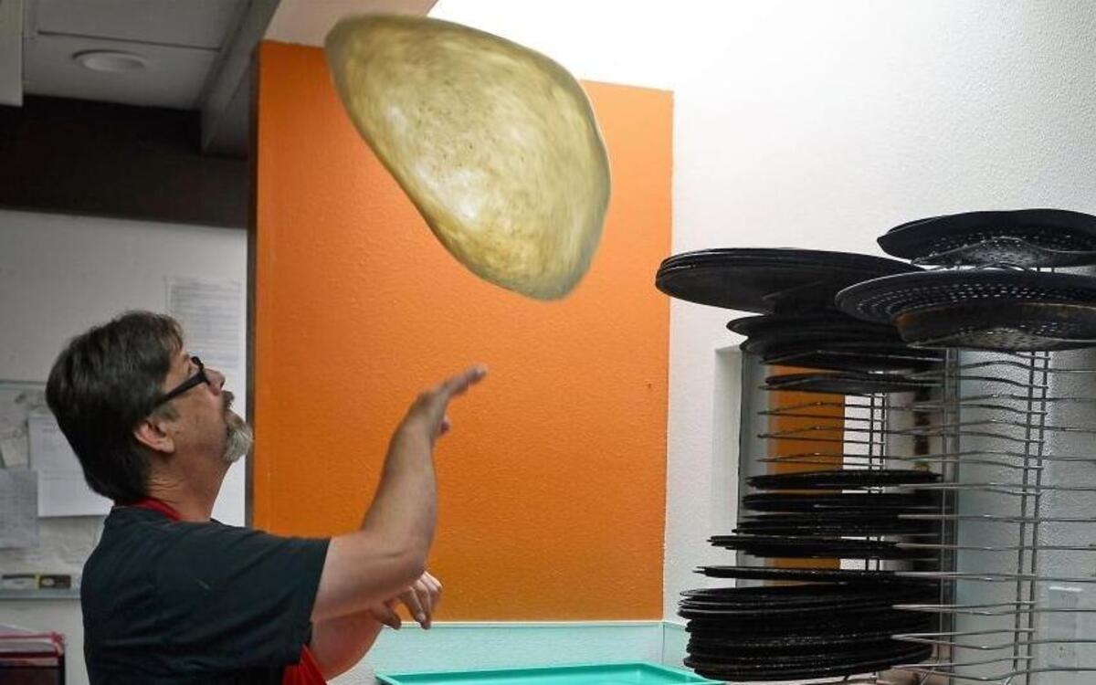 Darren Nichols of Nichols Pizza-N-Grill in Los Osos tosses dough Friday as he prepares pizza.