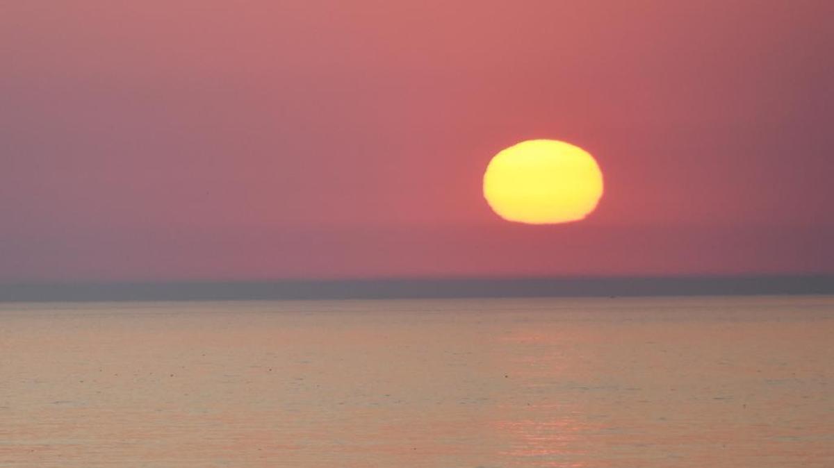 The sun sets over the Pacific Ocean on a hot summer night.