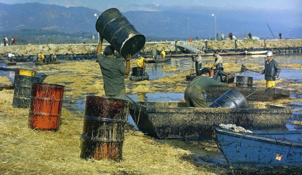 Workers collect oil-soaked straw from the beach at Santa Barbara Harbor on Feb. 7, 1969, following a leak from an offshore oil well. So far, 33 California coastal cities and counties have passed resolutions opposing expansion of offshore oil drilling. But not San Luis Obispo County.