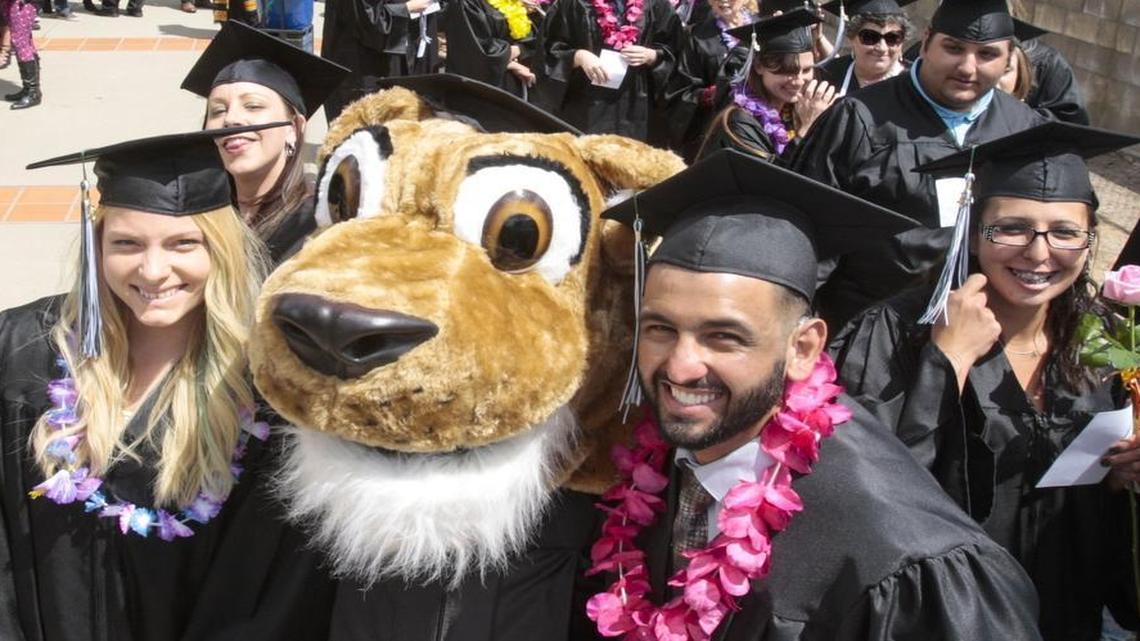 Cougie the Cougar poses with students before the May 2016 Cuesta College graduation.