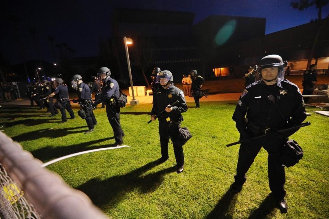 University of California police in riot gear line up on the other side of a fence from protesters outside Spanos Theatre at Cal Poly on Jan. 31, 2017.