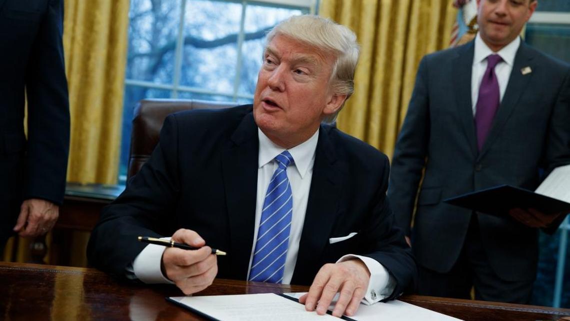 President Donald Trump signs an executive order to withdraw the U.S. from the 12-nation Trans-Pacific Partnership trade pact agreed to under the Obama administration, Monday, Jan. 23, 2017, in the Oval Office of the White House in Washington.