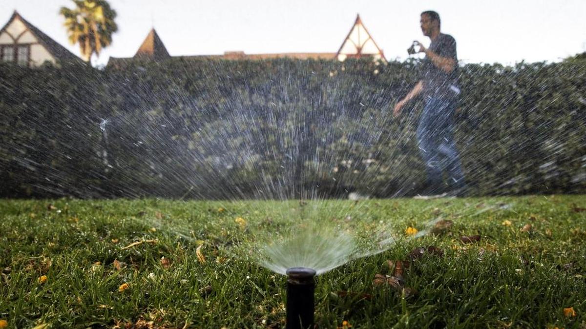 In this June 5, 2015, file photo, Tony Corcoran records sprinklers watering the lawn in front of a house in Beverly Hills. In the coming months of 2016, state officials will undertake a monumental task of rewriting conservation orders for a fifth year of drought.