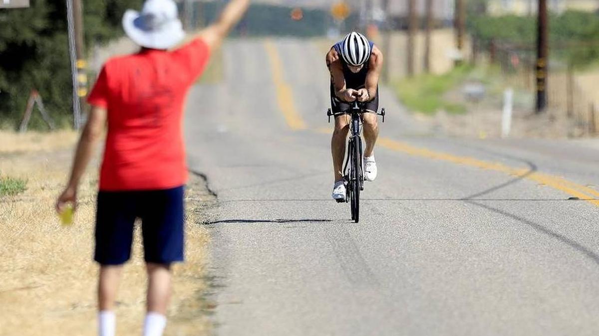 A bicycle racer approaches a water station on Orcutt Road at Biddle Ranch Road in rural San Luis Obispo during Saturday’s running of the 38th annual SLO Triathlon.