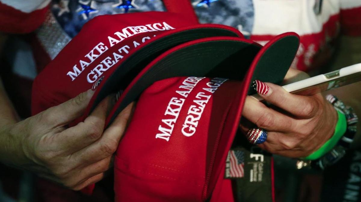 A woman holds hats to get them autographed by Republican presidential candidate Donald Trump during a rally in San Jose, Calif.
