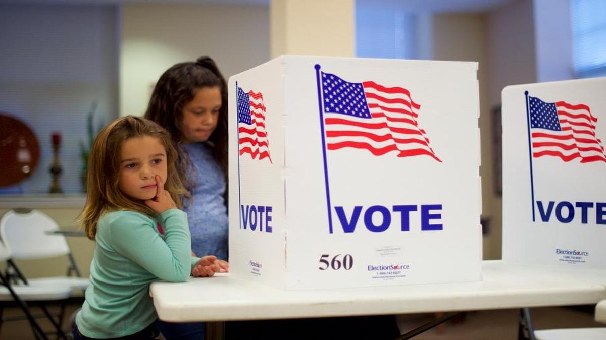 Angelina Blewitt, 5, left, and her sister, Mackayla, 9, wait Nov. 8 as their mother, Bridget, votes in Spring City, Pa.