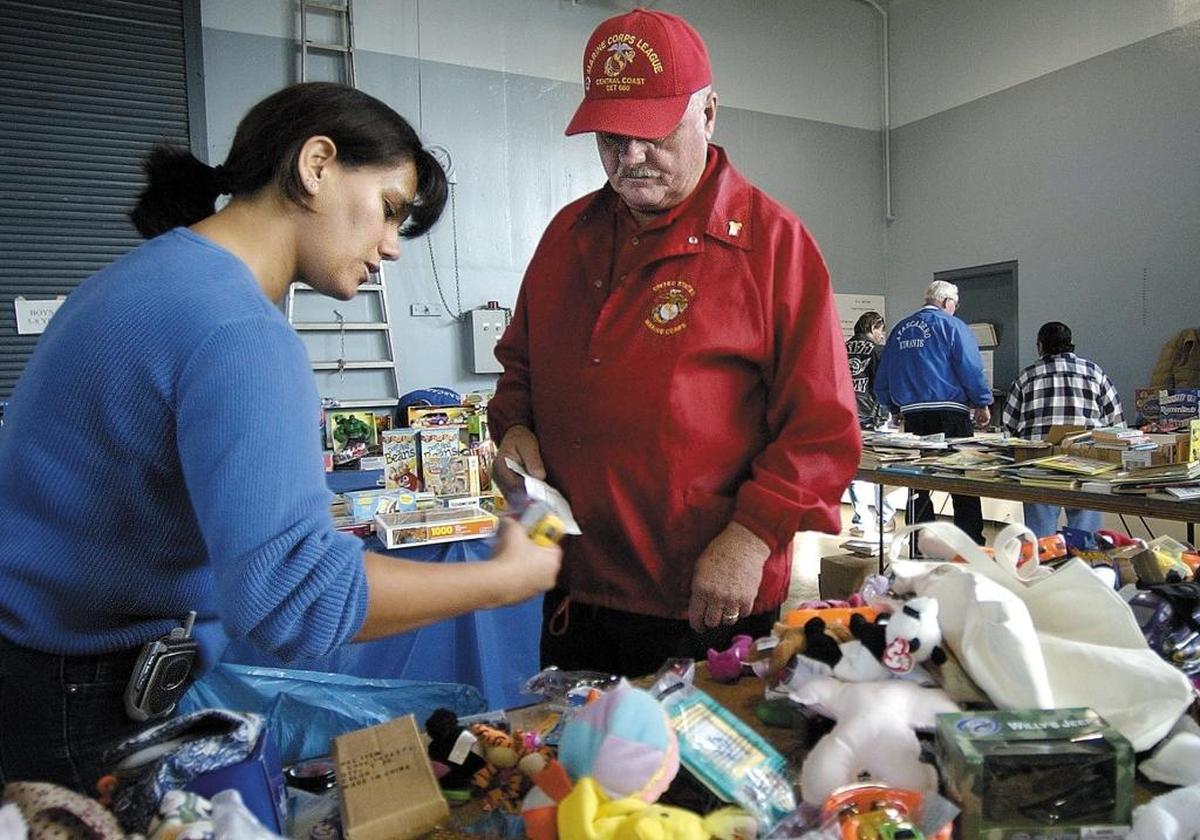 Angelica Castaneda picks out some gifts for her children with some help from Russ Tolchard at the Atascadero Loaves and Fishes, now ALF, charity formerly located at the National Guard Armory in Atascadero in 2004.