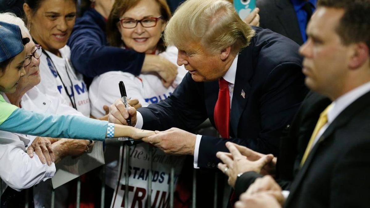 Republican presidential candidate Donald Trump signs a young girl’s arm after speaking at a campaign rally Saturday in Orlando, Fla.