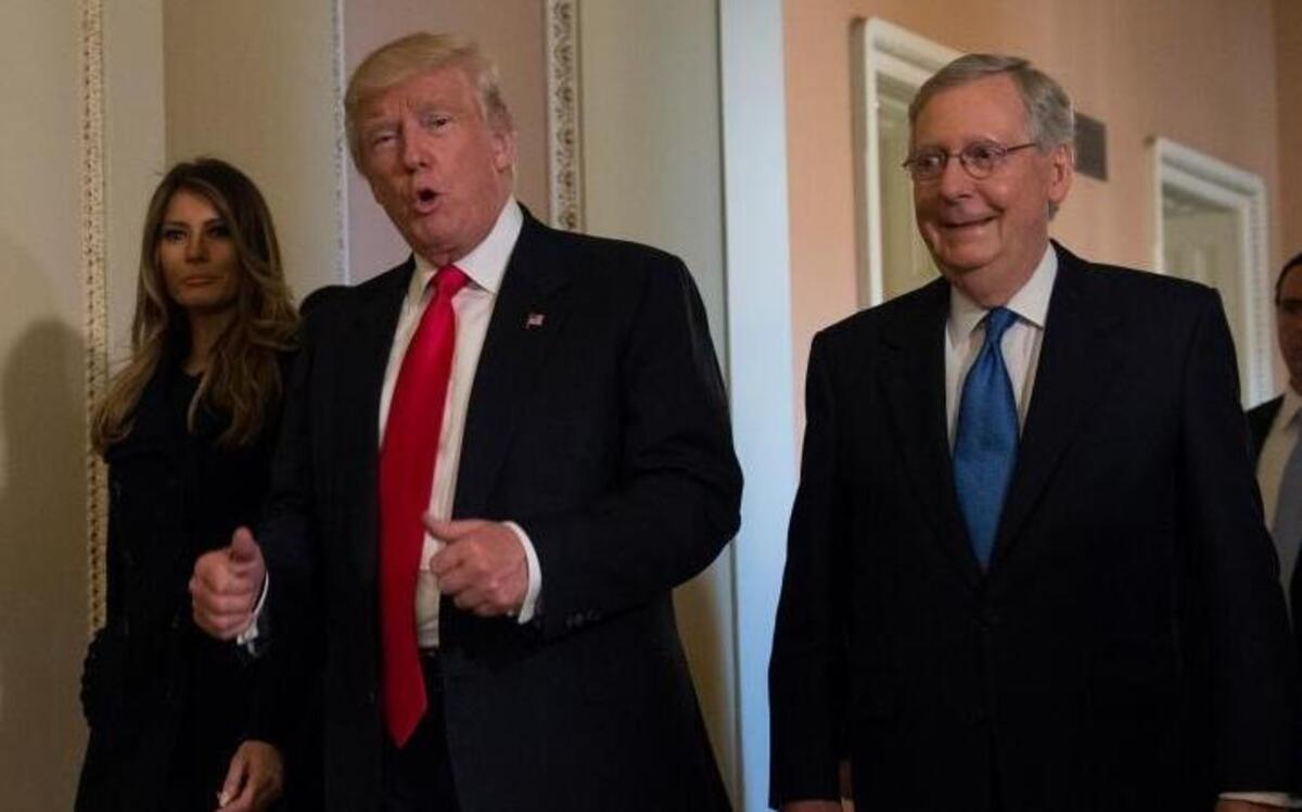 President-elect Donald Trump, accompanied by his wife Melania, and Senate Majority Leader Mitch McConnell of Ky., gestures while walking on Capitol Hill in Washington, Thursday, after meeting.