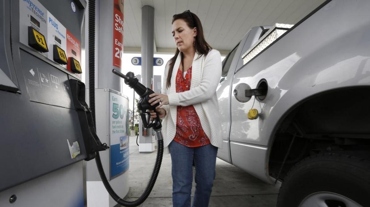 In this Nov. 12, 2014 file photo, Lydia Holland replaces the gas nozzle after filling up at a gas station in Sacramento, Calif.