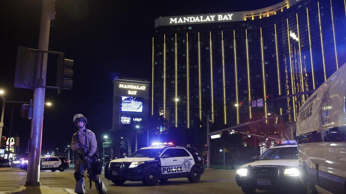 FILE - In this Sunday, Oct. 1, 2017 file photo, police officers stand along the Las Vegas Strip near the Mandalay Bay resort and casino during a shooting at a country music festival, in Las Vegas. Jay Purves and his colleagues at a private security firm manning the Route 91 Harvest festival Sunday night were a force of 200 unarmed first responders who lifted people over barriers, hid them behind pillars and under the stage, and funneled them to exits amid the panic. The guards are the first ones people inside an event go to when there is a problem.