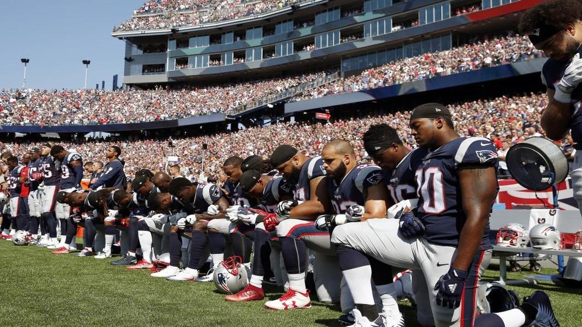 In this Sept. 24, 2017 photo, several New England Patriots players kneel during the national anthem before an NFL football game against the Houston Texans in Foxborough, Mass.